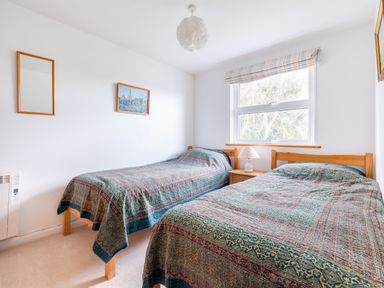 A bedroom with two single beds a bedside table with a lamp and a window at Slipway 21 in Rock