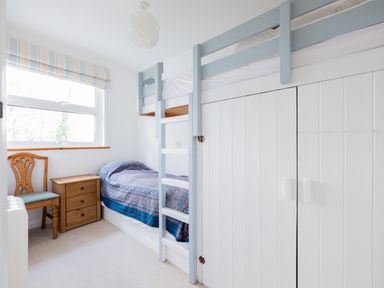 A small bedroom with a bunk bed a wooden chair and a bedside table at Slipway 21 in Rock