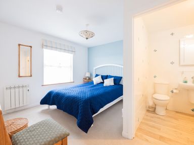 A bedroom with a blue bedspread and two pillows next to a bathroom at Slipway 21 in Rock