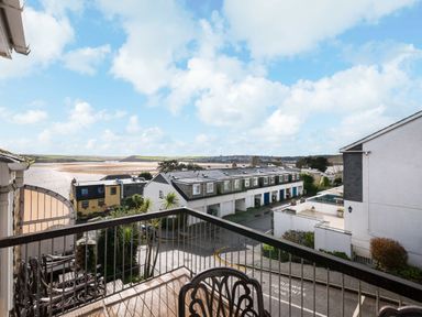 View from a balcony with a metal railing overlooking a street with houses and an estuary in the background at Slipway 21 Rock