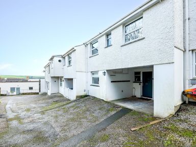 A row of white buildings with covered parking areas and blue doors at Slipway 21 in Rock
