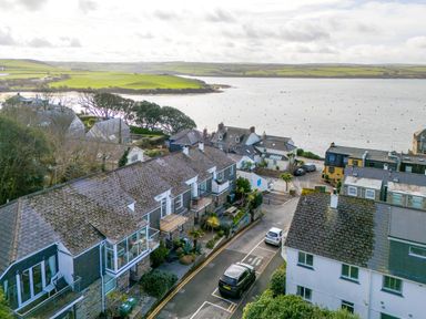 A coastal residential area with houses parked cars and a body of water with hills in the background at Slipway 21 in Rock