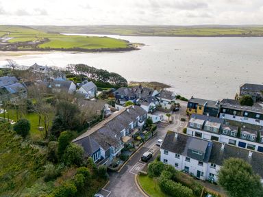 A coastal village with houses near water and green fields in the distance at Slipway 21 in Rock