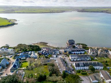 Aerial view of a coastal village with houses near estuary and green fields in the background at Slipway 21 in Rock