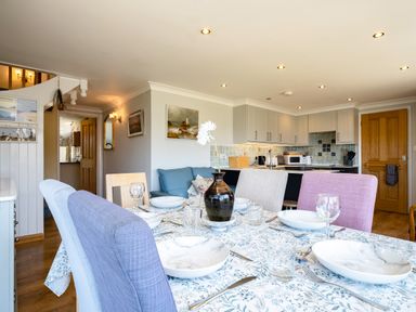 A dining table with chairs and tableware in a kitchen and dining area at Little Belz in Polzeath