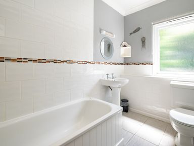 A bathroom with a bathtub sink toilet window and mirror at Little Belz in Polzeath