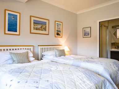 A bedroom with two single beds and framed pictures on the wall at Little Belz in Polzeath