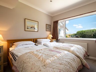 A bedroom with two single beds side by side under a large window at Little Belz in Polzeath