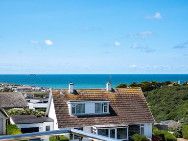 A house with a tiled roof near the sea with a clear sky at Little Belz in Polzeath