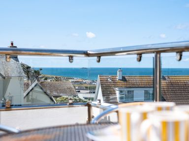 A balcony railing with a view of rooftops and the ocean in the distance at Little Belz in Polzeath