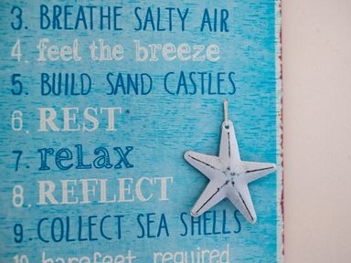 A blue sign with a list of beach activities and a hanging starfish decoration on the right