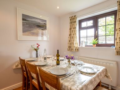 A dining room with a table set for six including plates and glasses and a window with curtains at Hazelhurst in Rock