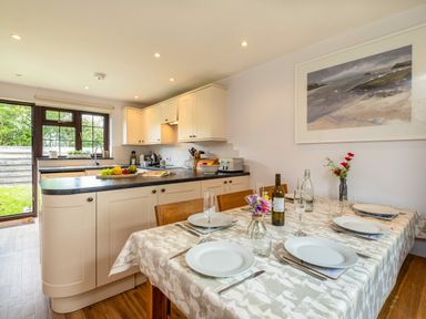 A kitchen with white cabinets and black countertops next to a dining table set with white plates glasses and cutlery at Hazelhurst in Rock
