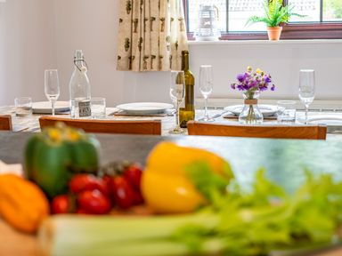 A dining table set with plates glasses and a bottle with vegetables on the counter in the foreground at Hazelhurst in Rock