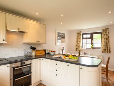 A kitchen with white cabinets black countertop and a dining table near a window at Hazelhurst in Rock