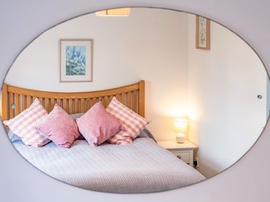 A bedroom with a wooden bed frame four pink pillows a bedside table with a lamp and framed pictures on the wall at Hazelhurst in Rock