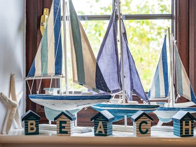 A window sill with model sailboats starfish and wooden blocks spelling beach at Hazelhurst Rock
