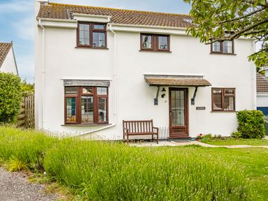 A white two-story house with brown windows a bench outside and green lawn at Hazelhurst in Rock