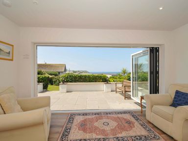 A living room with a view of the patio and ocean at Sunset in Polzeath