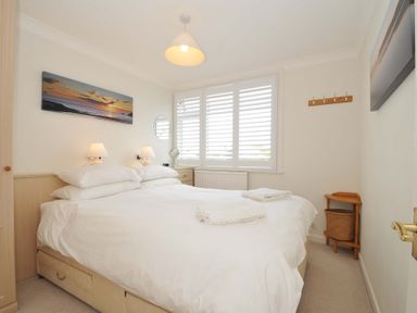 A bedroom with a bed and bedside lamps at Sunset in Polzeath