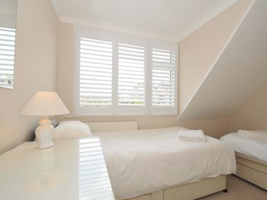 A bedroom with two single beds and a window at Sunset in Polzeath