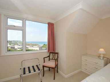 A bedroom with a window and chair at Sunset in Polzeath