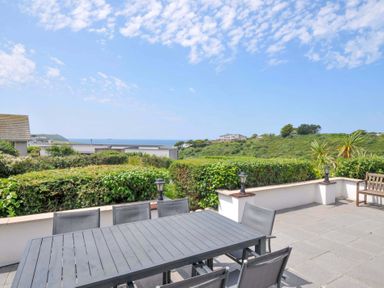 A patio with a dining table and chairs at Sunset in Polzeath