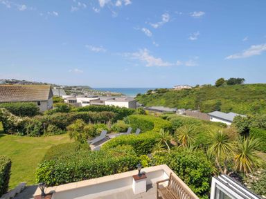A view of a garden and houses near the sea at Sunset in Polzeath
