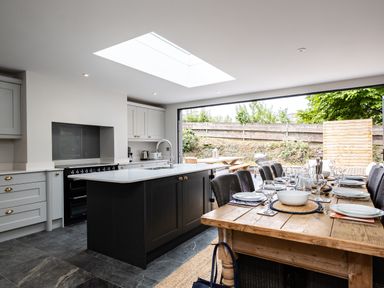 A kitchen with an island and dining table set with plates and glasses at Porthilly Greys in Rock