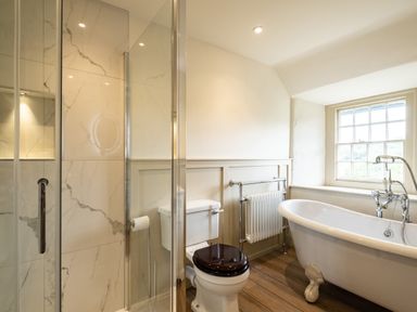 A bathroom with a shower, toilet, freestanding bathtub, and a window at Porthilly Greys in Rock