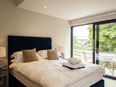 A bedroom with a bed with pillows and folded towels near a sliding glass door at Porthilly Greys in Rock