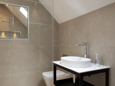 A bathroom with a wall-mounted toilet and a sink with a faucet on a countertop with soap at Porthilly Greys in Rock