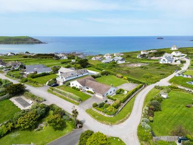 A coastal residential area with houses grassy lawns and roads near the sea at Trebartha in Daymer Bay