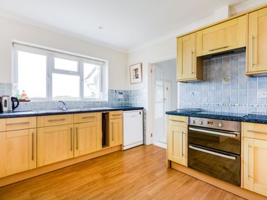 A kitchen with wooden cabinets a dishwasher an oven and a window at Trebartha in Daymer Bay