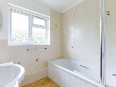A bathroom with a bathtub shower combo a window and a sink at Trebartha in Daymer Bay