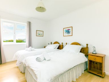A bedroom with two single beds with white bedding and wooden headboards at Trebartha in Daymer Bay