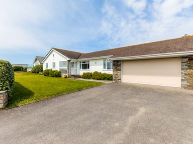 A single story house with a driveway and lawn at Trebartha in Daymer Bay