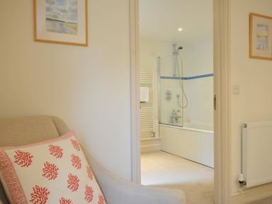 A view of a bathroom with a bathtub and shower from a living area at Farlands in Daymer Bay