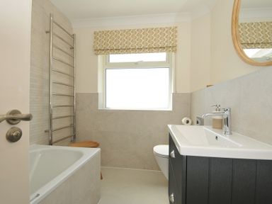 A bathroom featuring a tub, toilet, sink, and towel rail at Farlands Daymer Bay