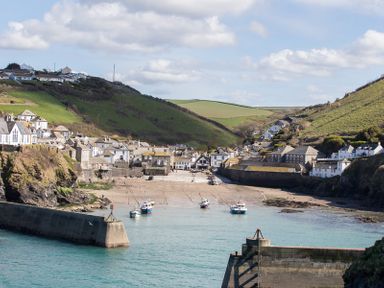 A coastal village with boats in the water and houses on green hills at The Granary in Rock