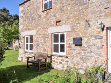 An exterior view of a stone building with a bench at The Granary Rock
