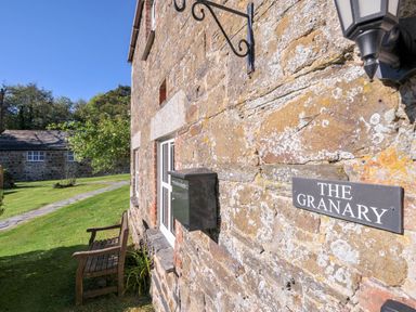 Exterior view of The Granary with a stone wall and bench at The Granary in Rock
