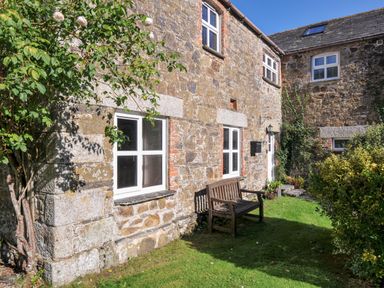 A garden with a bench and plant next to a stone wall at The Granary Rock