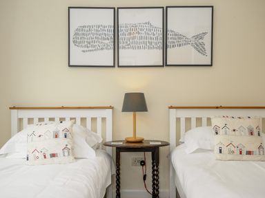 A bedroom with two single beds a side table with a lamp and three framed pictures of a fish on the wall at Trevega in Polzeath