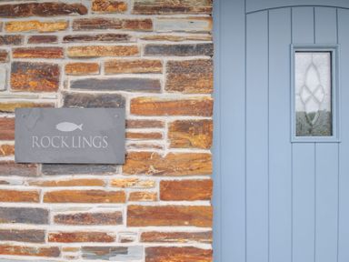 A stone wall with a blue door and a nameplate at Rocklings in Rock