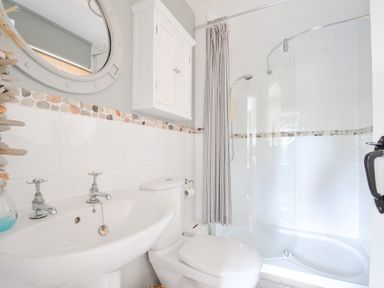 A bathroom with a sink, toilet, shower, and mirror at Rocklings, Rock