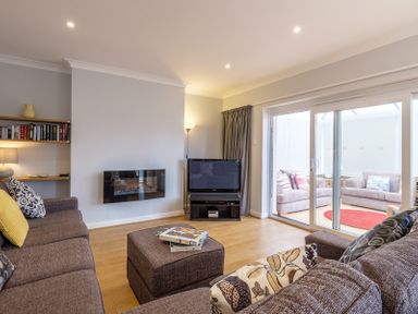 A living room with brown sofas and a television next to glass sliding doors at Cogenhoe in Rock