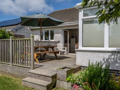 A wooden deck with picnic table and umbrella outside a house at Cogenhoe Rock
