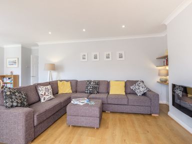 A living room with a large sectional sofa and cushions a floor lamp and framed pictures on the wall at Cogenhoe in Rock