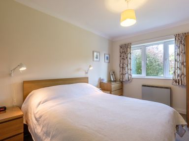 A bedroom with a bed chest of drawers lamps and a window with curtains at Cogenhoe in Rock